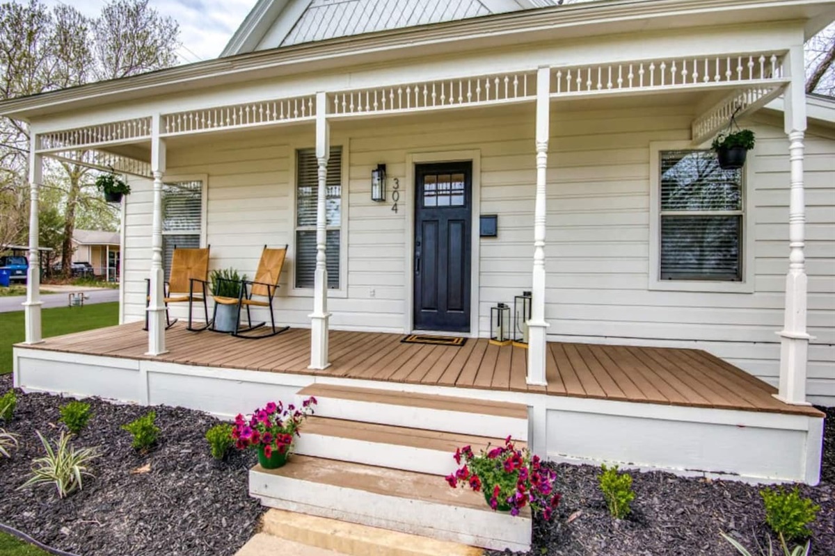 Welcoming covered front porch with seating, navy front door, flower boxes, and classic farmhouse trim. Modern farmhouse rental in downtown Aubrey TX near Frisco, Denton, and top Denton County wedding venues. Sleeps up to 7 guests.