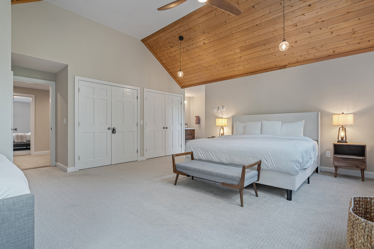 King bedroom with vaulted wood ceiling, bench seating and double closets
