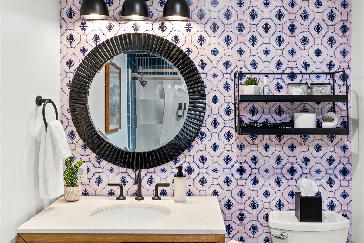 Charming bathroom with spacious tub and shower with bold wallpaper and modern fixtures.