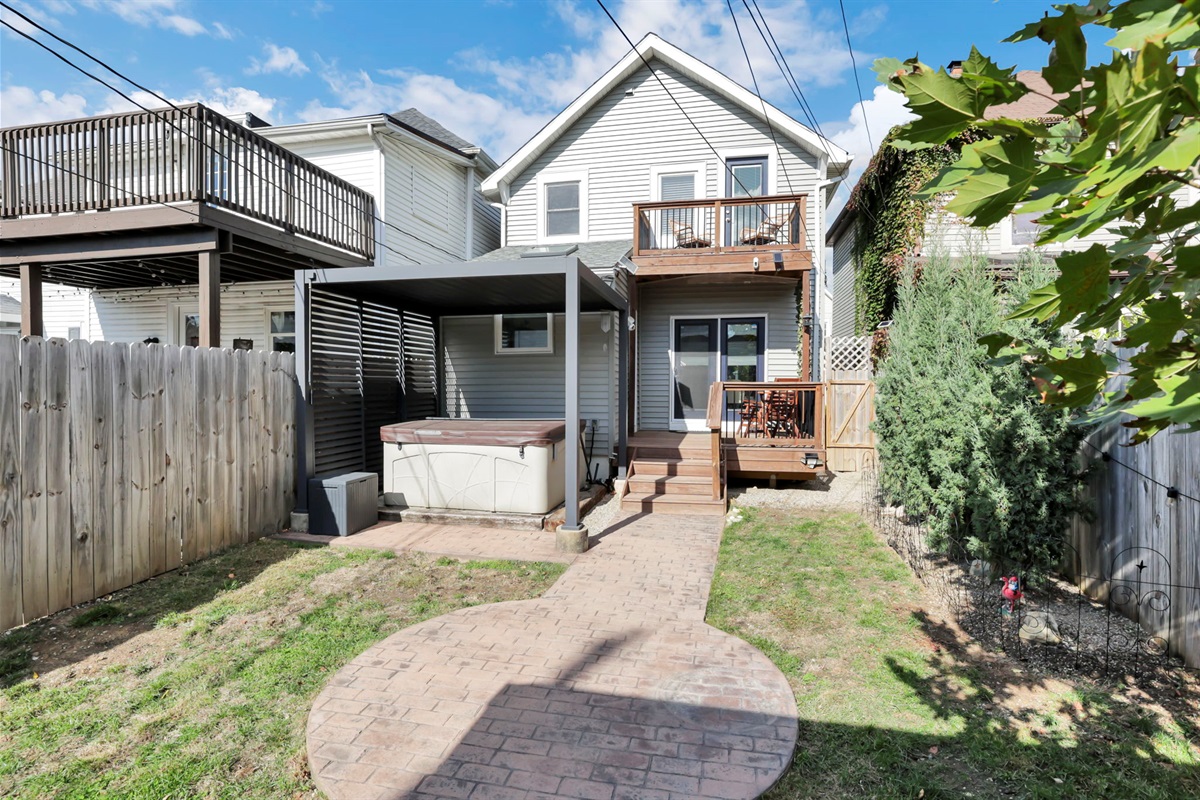 A full view of the back yard with hot tub, deck, and balcony