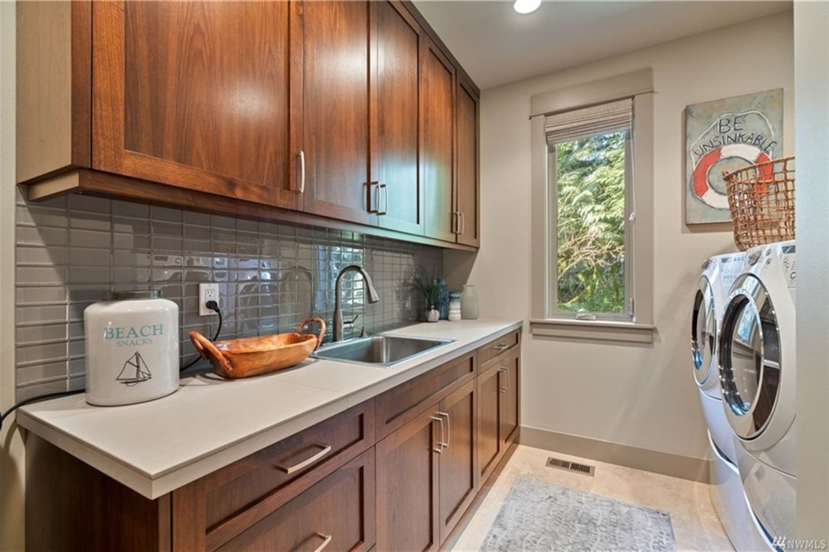 Spacious laundry room featuring a large-capacity washer and dryer, with laundry detergent provided.