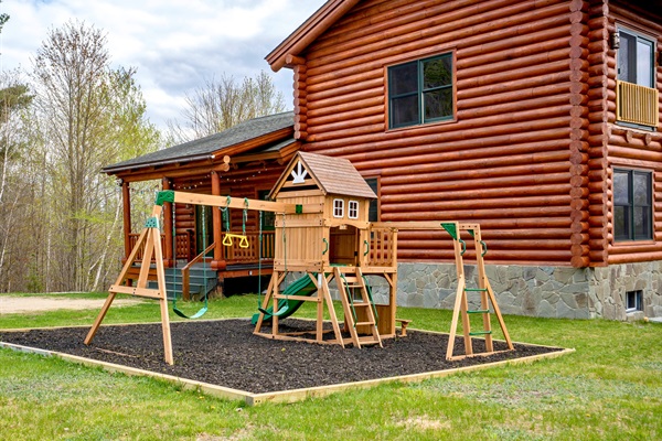A spacious backyard playground designed for endless fun, complete with swings, climbing features, and a slide for little ones to enjoy.