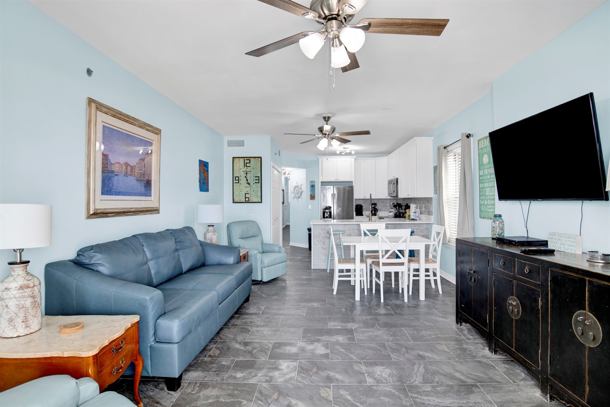 Living room with wall mounted smart TV, 2 ceiling fans, leather sleeper sofa, 2 leather rocker recliners and balcony access with breathtaking view