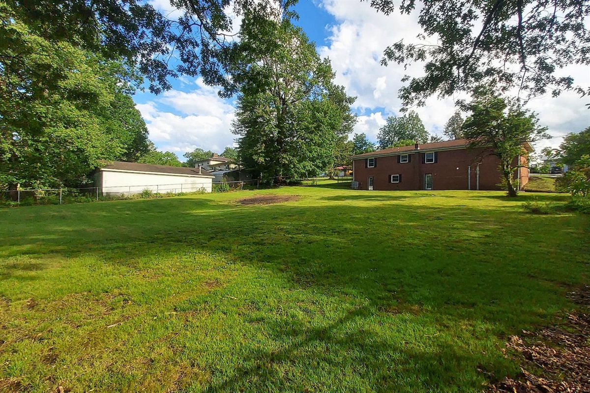 This photo was taken from the far corner of the yard to showcase just how spacious, open, and beautiful the half-acre property truly is—a peaceful slice of the outdoors, perfect for enjoying the view or just soaking up the quiet.