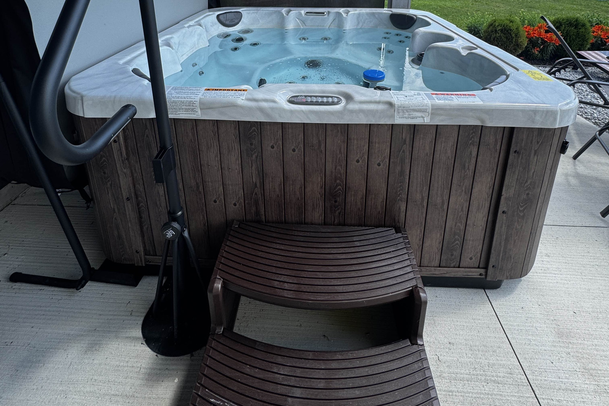 Enjoy easy access to this private outdoor hot tub, featuring built-in steps and a sturdy handrail for comfort and convenience. Perfectly set on a waterfront patio, it offers a relaxing spa experience surrounded by fresh air and peaceful canal-side views.