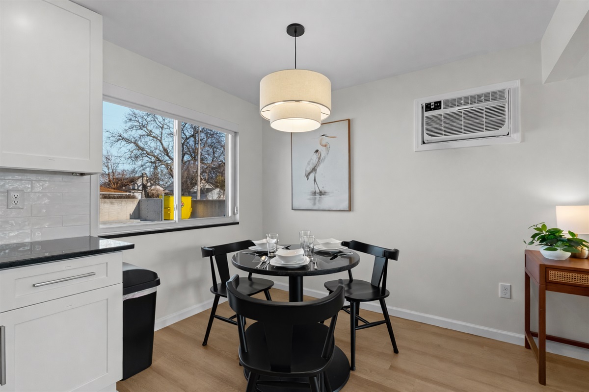 Charming dining nook with modern lighting, cozy seating for four, and natural light—perfect for shared meals, morning coffee, or casual evenings in.