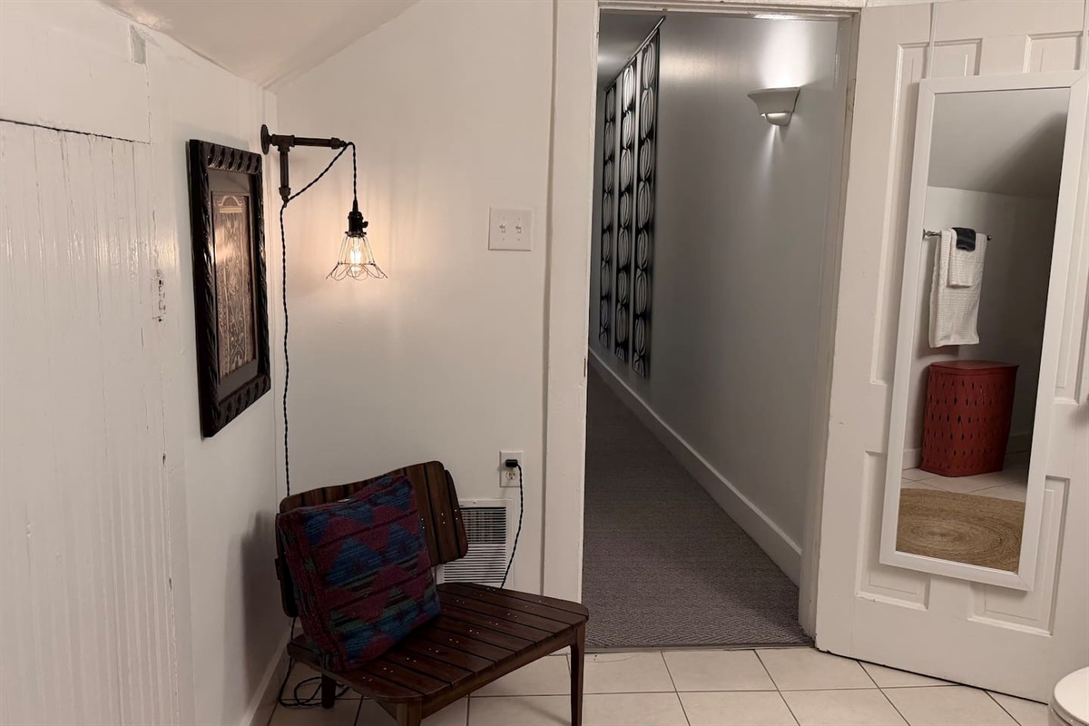 An unusually spacious bathroom with a full-length mirror and a small lounge chair — a comfortable place to slow down, get ready, and settle in.