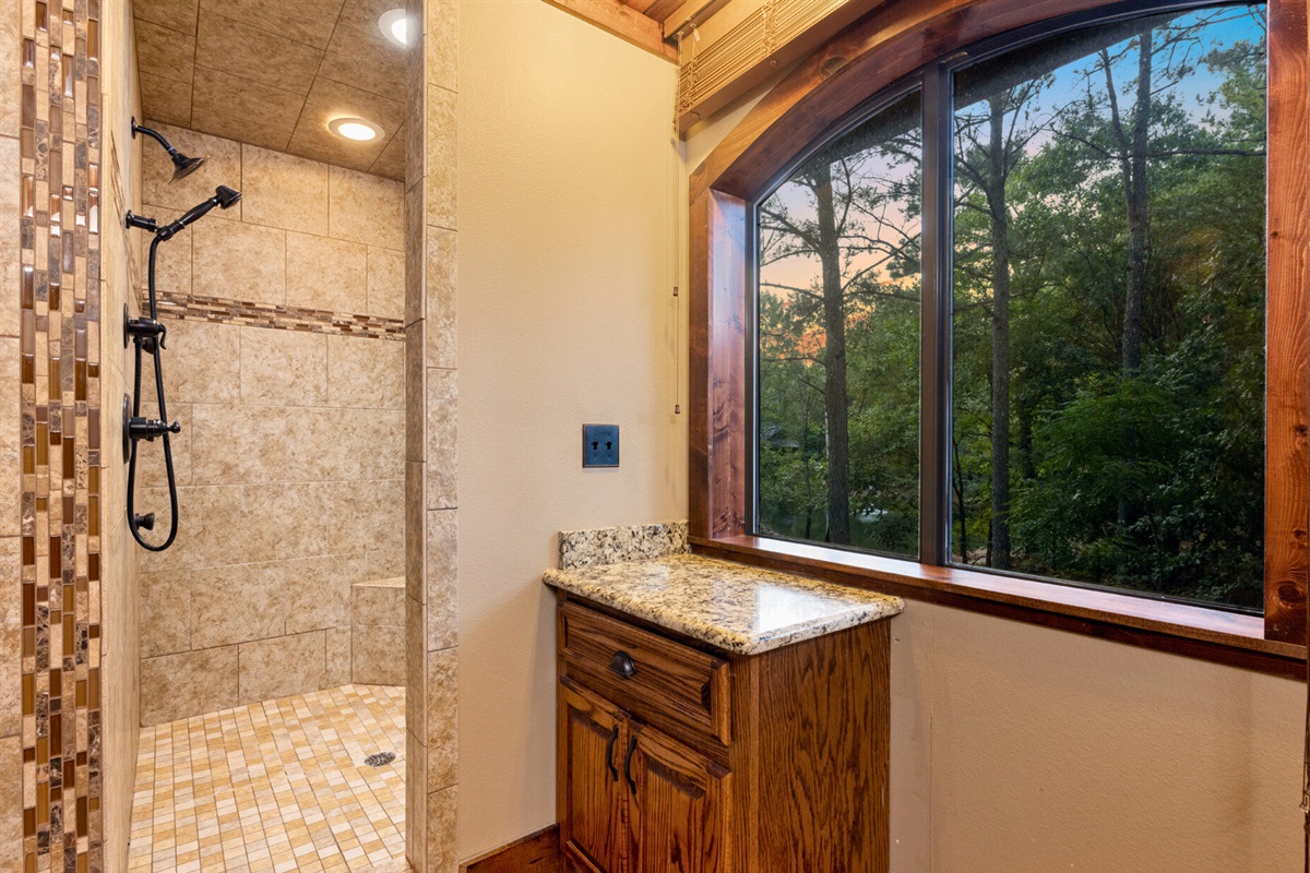 Bright tiled bathroom with forest views—shower with nature.