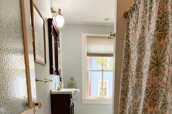 The full bath on the second floor — generous proportions, a Persian runner, and a shower curtain that holds its own in a house full of good taste.
