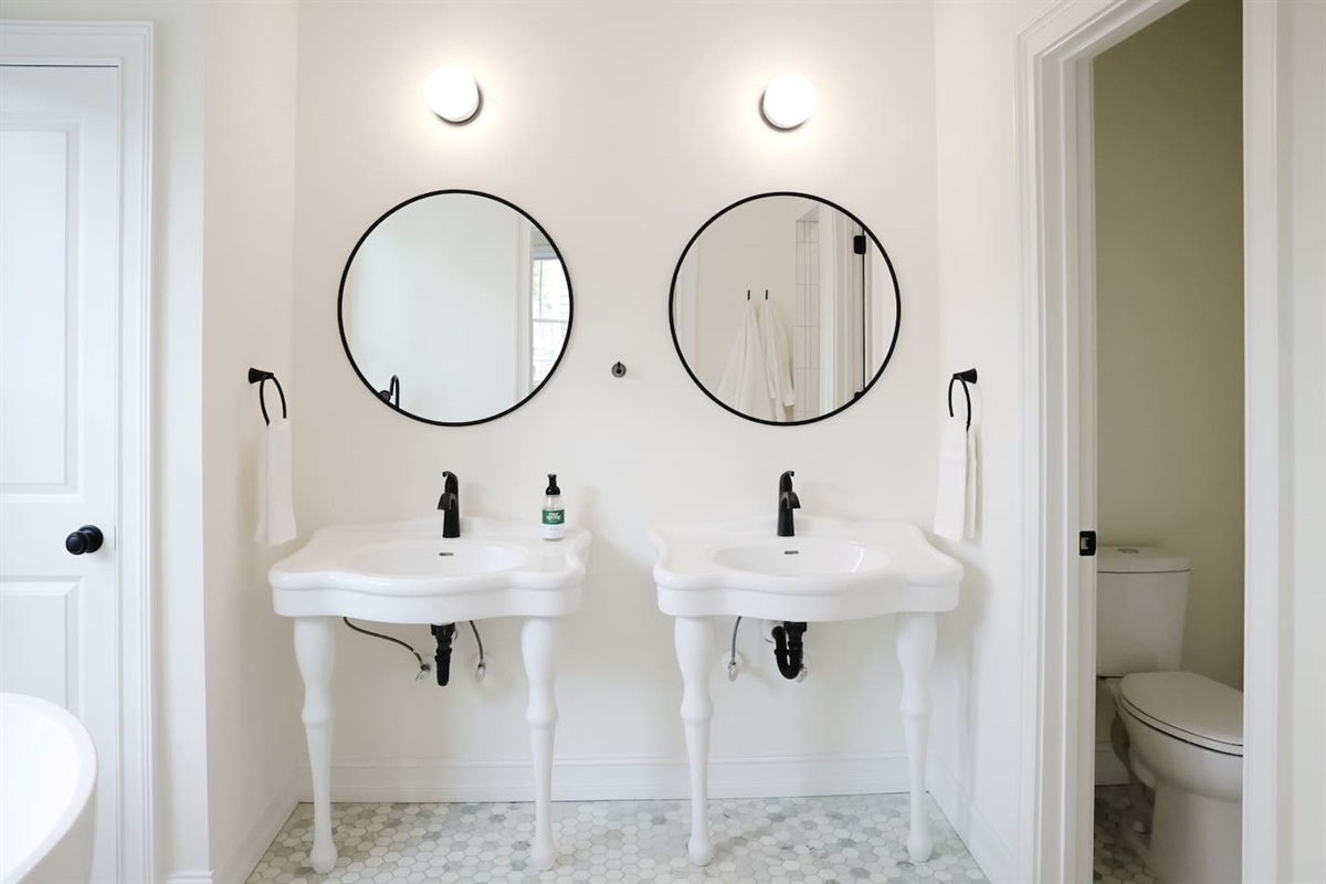 The primary bathroom features dual vanities, a private toilet area, a stand up shower and a soaking tub.
