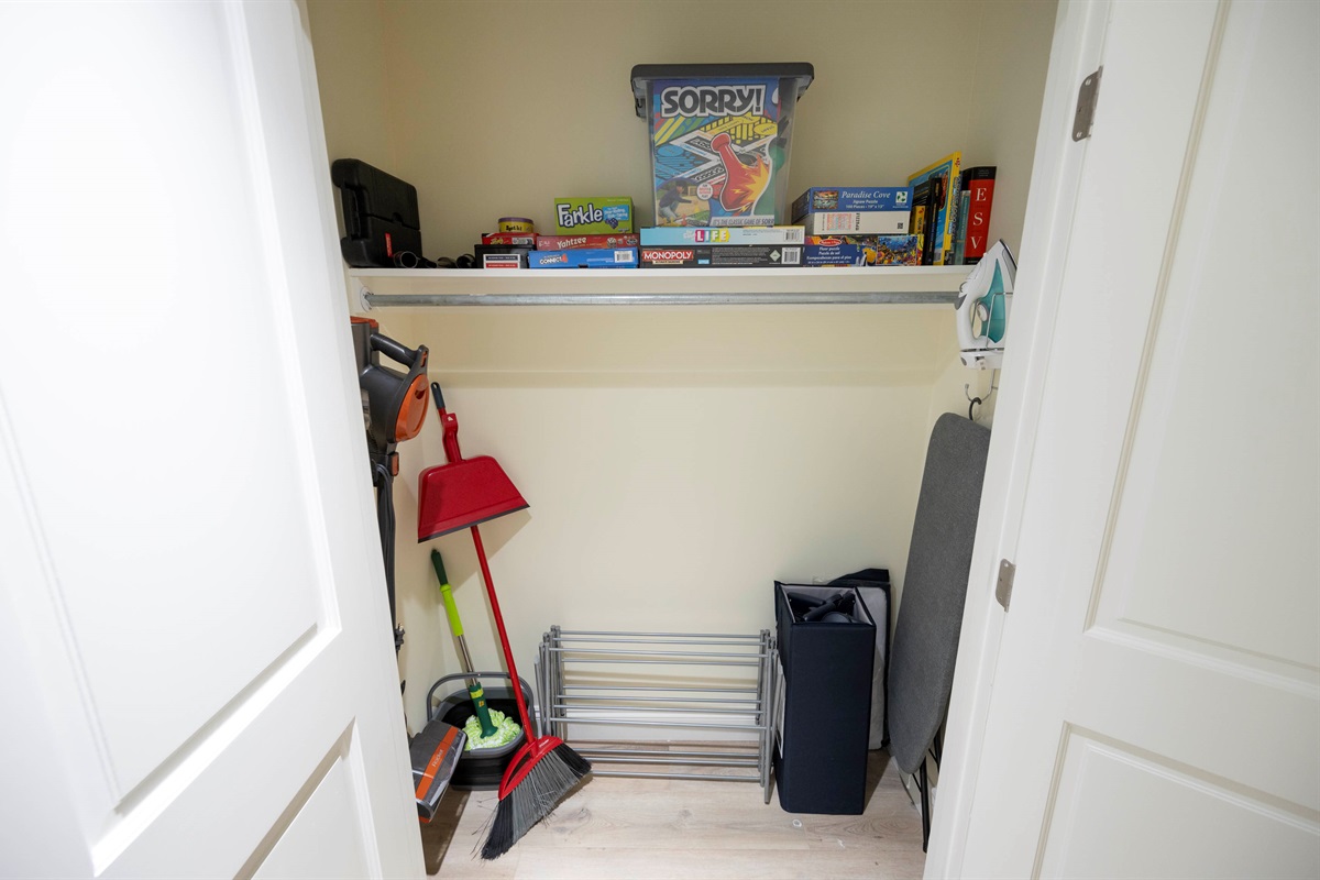 Organized storage closet with games, cleaning tools, and household essentials.