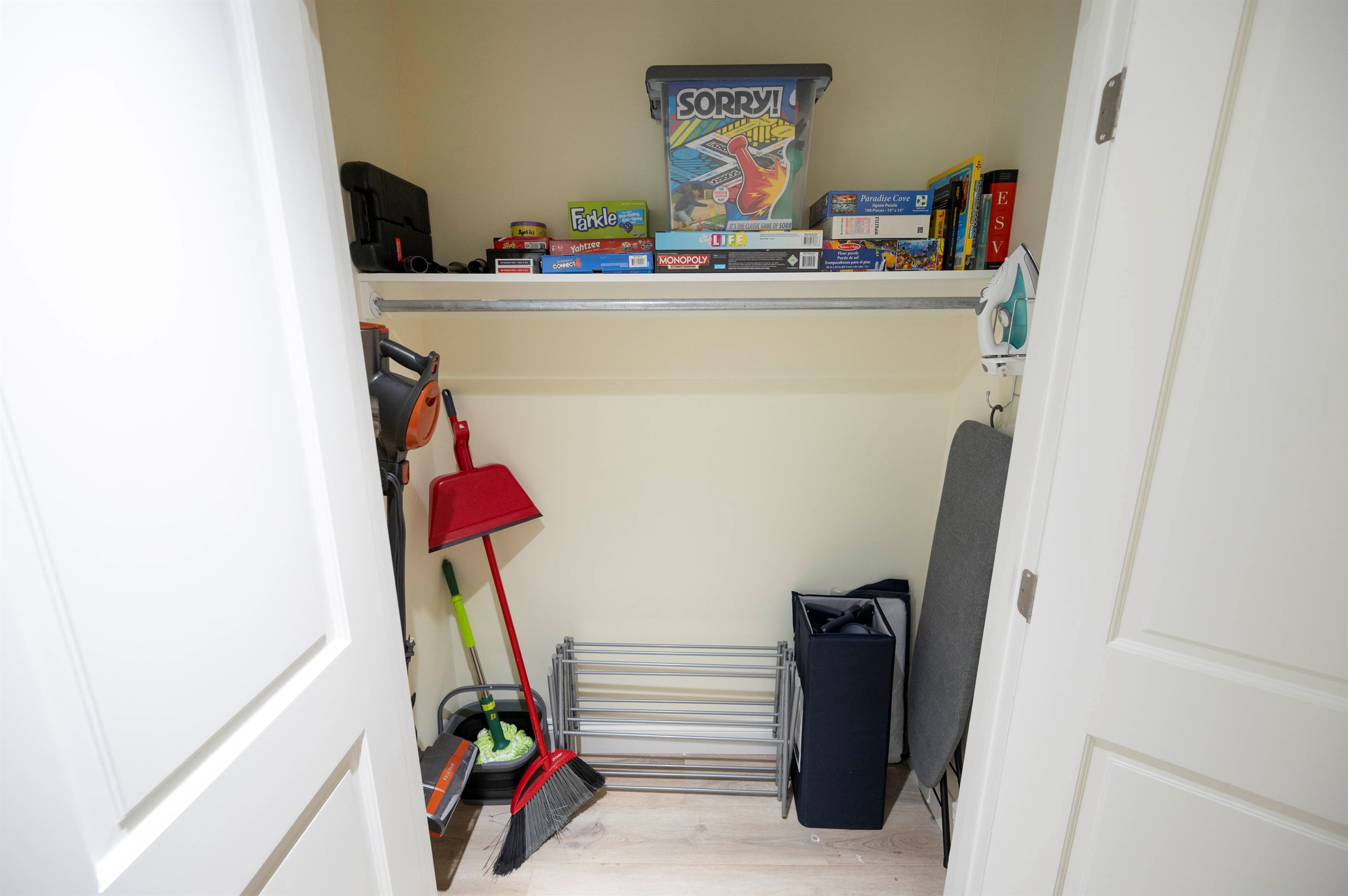 Organized storage closet with games, cleaning tools, and household essentials.