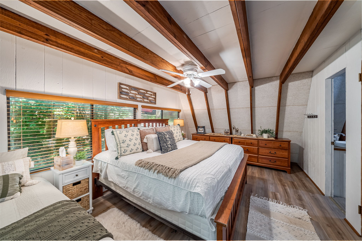 Your main floor King is where you'll sleep harder than you have in months — exposed beam ceiling, luxury vinyl plank floors, and the lakeshore right outside.