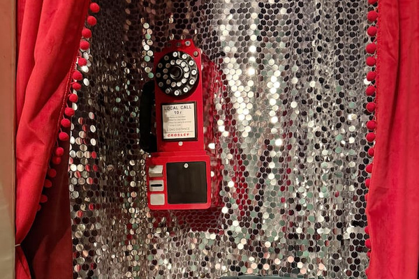 Hidden speakeasy photo booth with vintage rotary phone and glittering disco walls. One of  the most Instagrammable spots in this unique New Orleans Airbnb—perfect for girls trips,  bachelorettes, and celebration weekends. 