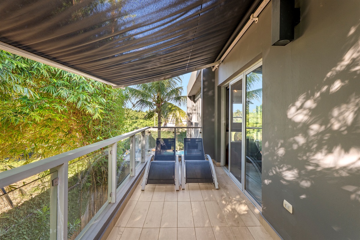 Shaded balcony surrounded by greenery.