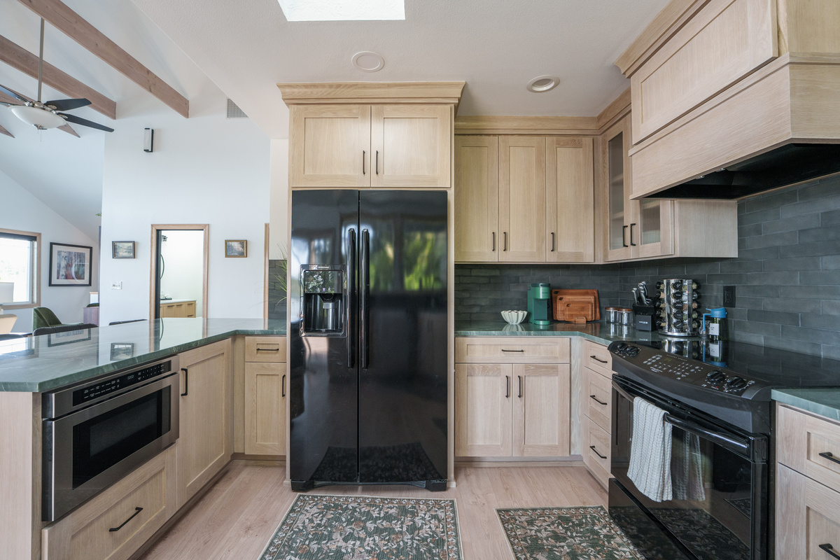 Fully equipped kitchen with modern appliances, generous counter space, and large windows that fill the room with natural light. Coffee station includes Keurig k-cup pods and traditional ground coffee maker