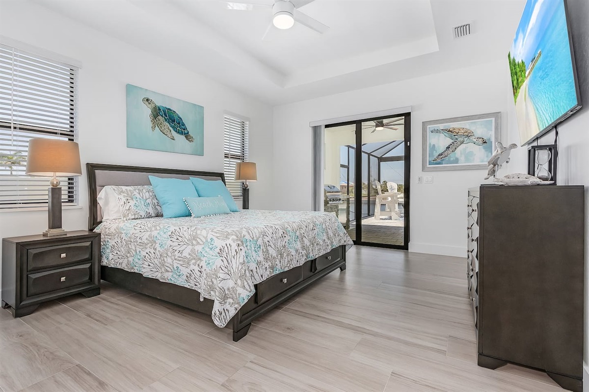 Stunning primary suite featuring a king-size bed, a TV, and direct access to the lanai and pool area!