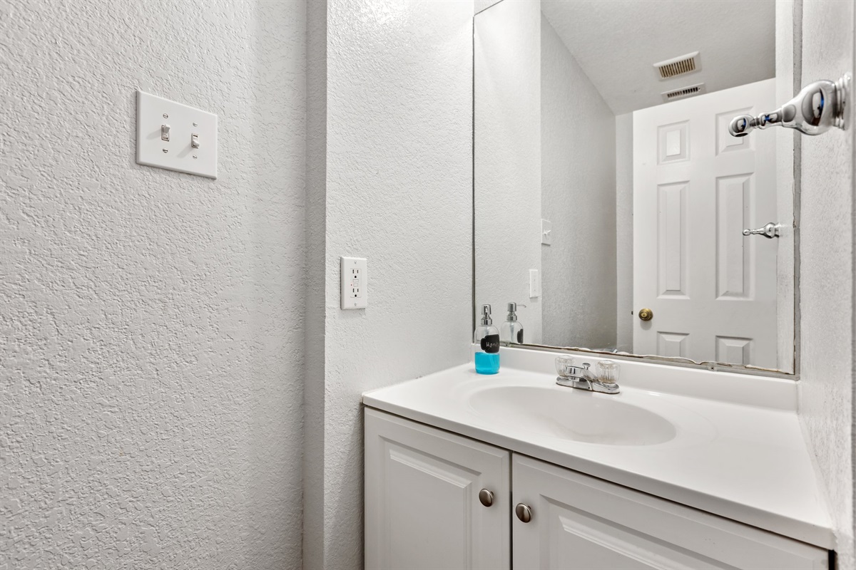 Downstairs half bathroom with vanity, sink, and storage. Fresh towels and essentials provided for every guest at this San Antonio rental.