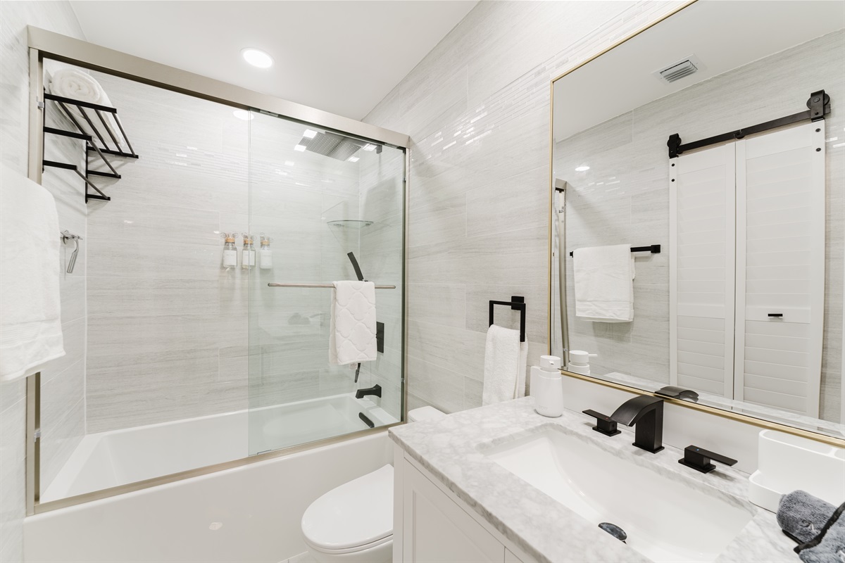 Spa-style **2nd bedroom ensuite bathroom** featuring a sleek glass-enclosed shower with rainfall head, marble vanity, and hotel-quality towels—clean, modern, and effortlessly relaxing.