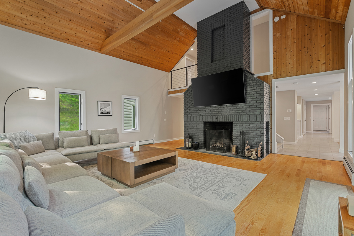 Living room with floor-to-ceiling brick fireplace and 86-inch TV at First Chair Lair
