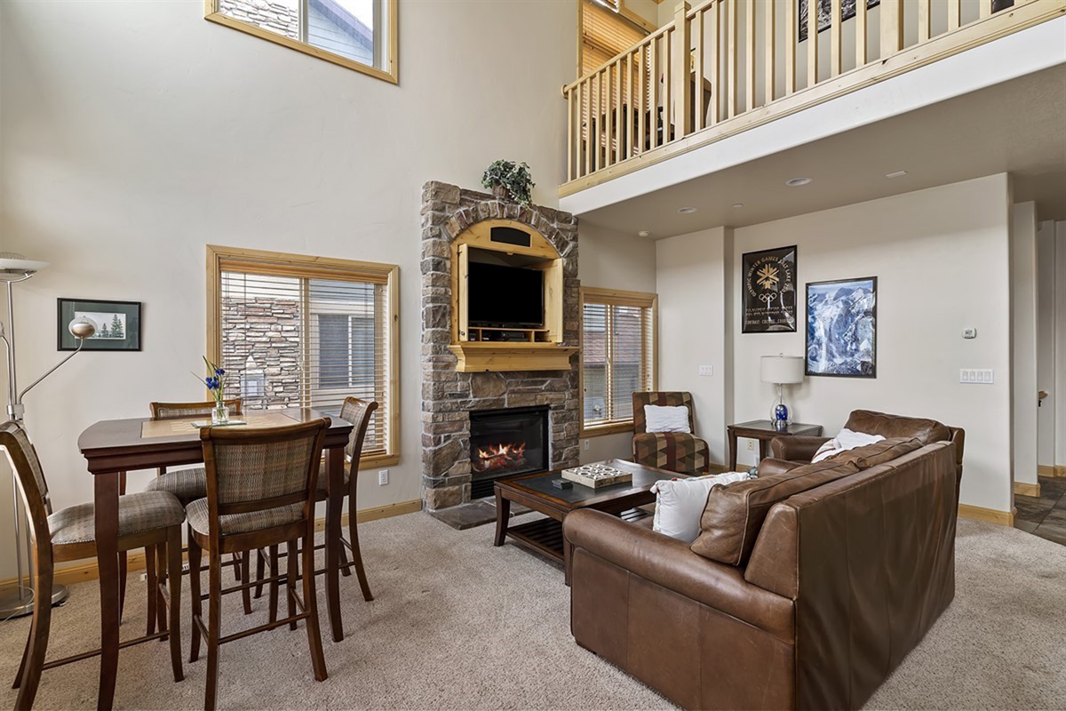 Bright and airy great room with dramatic ceilings and abundant natural light, with cozy fireplace creating a welcoming and luxurious ambiance.