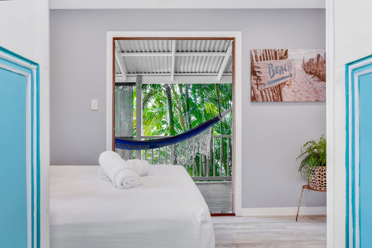 A queen bed and direct doorway to the covered balcony make this bedroom at Aaron's Beachside Boat House a well-connected part of the lower-level layout.