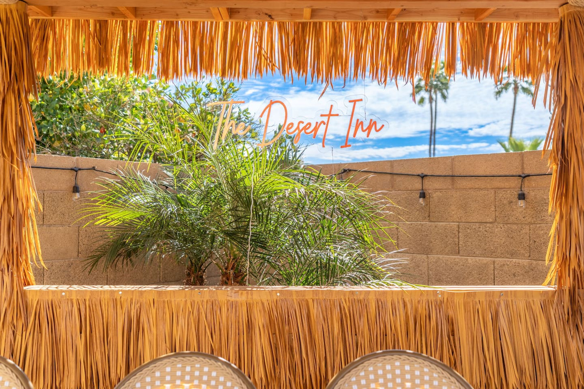 Tropical tiki bar with thatch roof, desert views, and signature branding—the ultimate outdoor hangout space.