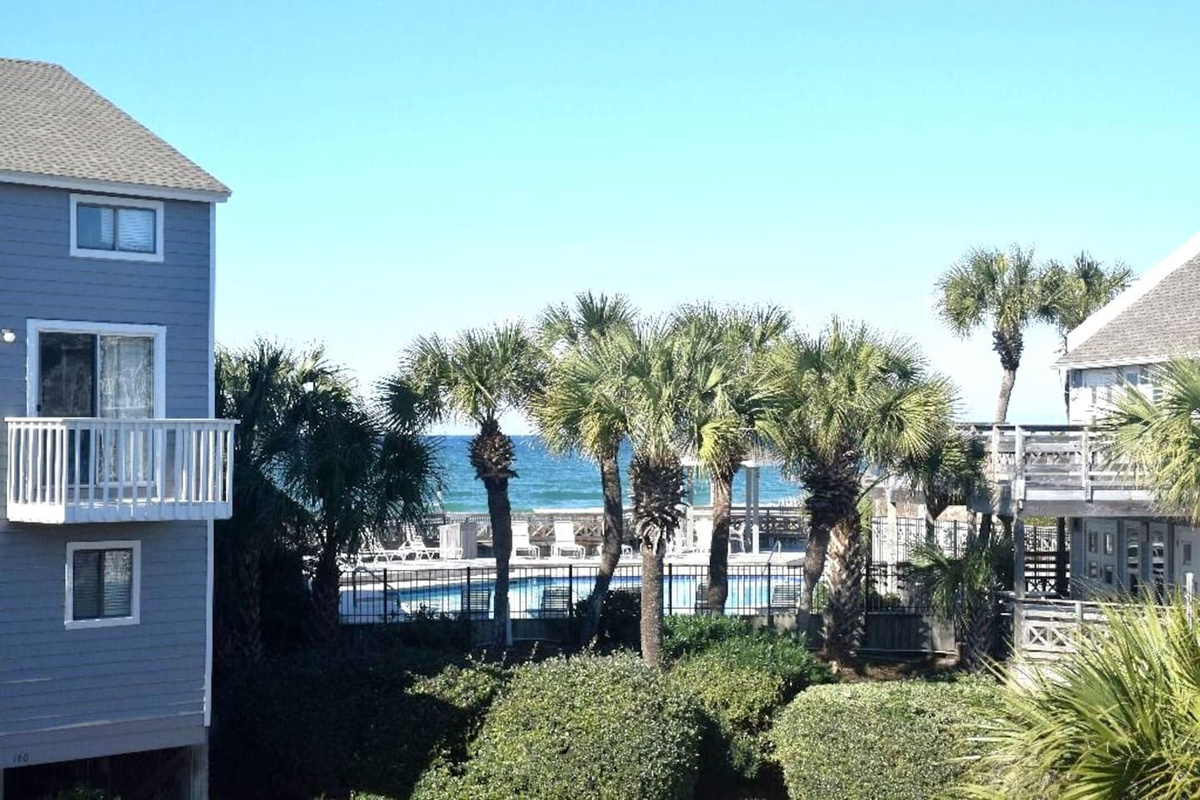 Step outside and this is your view &mdash; palm trees, the beachfront pool, and the Gulf of Mexico glittering in the distance. The beach is 40 steps from here.