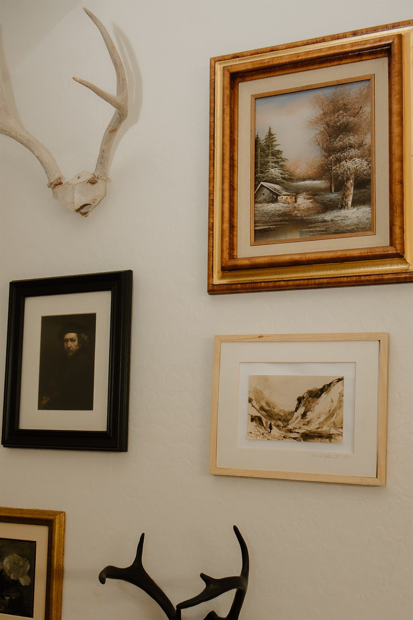 Curated gallery wall with vintage landscape art and shed antlers in this Pinetop-Lakeside luxury townhome. Authentic Arizona hunting lodge character throughout this White Mountains vacation rental with thoughtful design details.