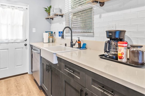 Our kitchen boasts a modern sink and dishwasher, ensuring easy cleanup and convenience. Don’t forget the coffee maker for your daily caffeine fix, all enhanced by a lively plant that brightens up the room!