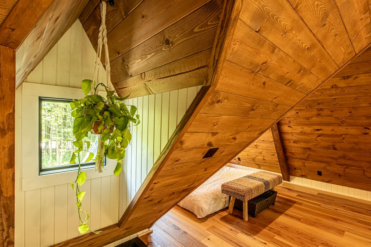 Adding a playful touch, a hammock is ingeniously built into the floor, perfect for lounging and soaking in the serene atmosphere. Nearby, a macrame swing hangs, providing a cozy nook to relax and sway gently while enjoying the tranquil forest view.