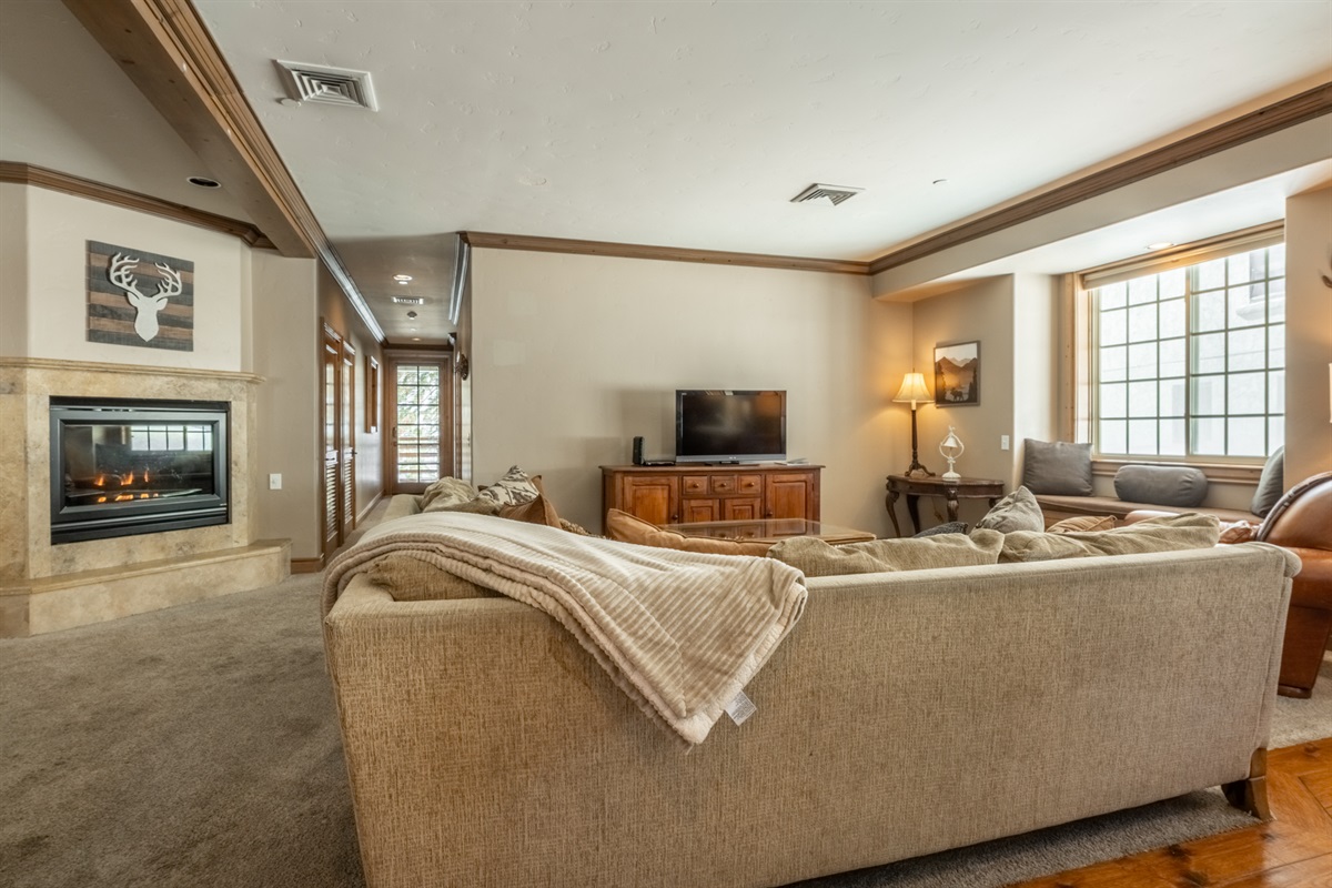 A warm, inviting living space anchored by a gas fireplace and oversized windows—designed for gathering, relaxing, and unwinding after a day on the mountain.
