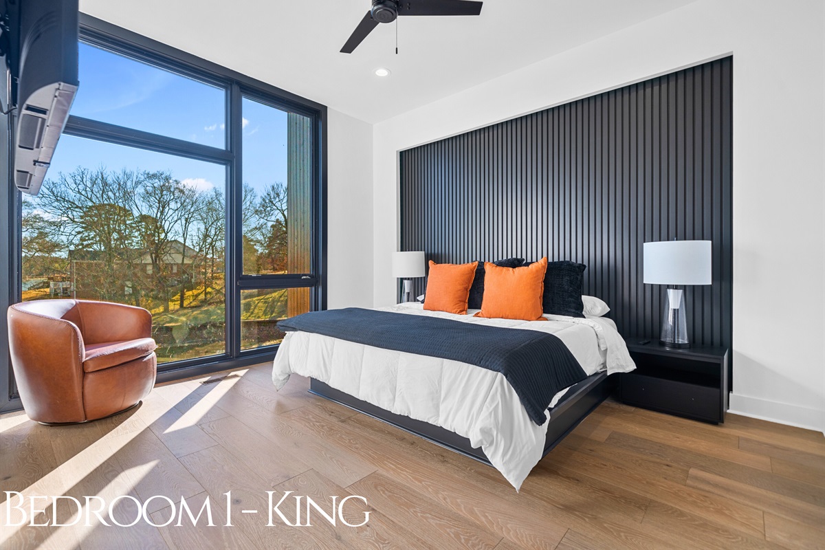 A king bedroom retreat with plush bedding, bold accents, and oversized windows that flood the space with light, creating a truly serene and luxurious atmosphere.