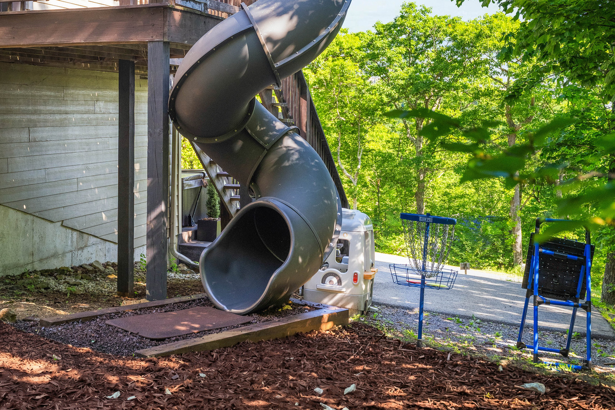 Tucked into the trees next to the entrance deck, the slide and play area give the home its own little adventure zone — perfect for keeping the fun going between hikes, ski runs, and hot tub time.