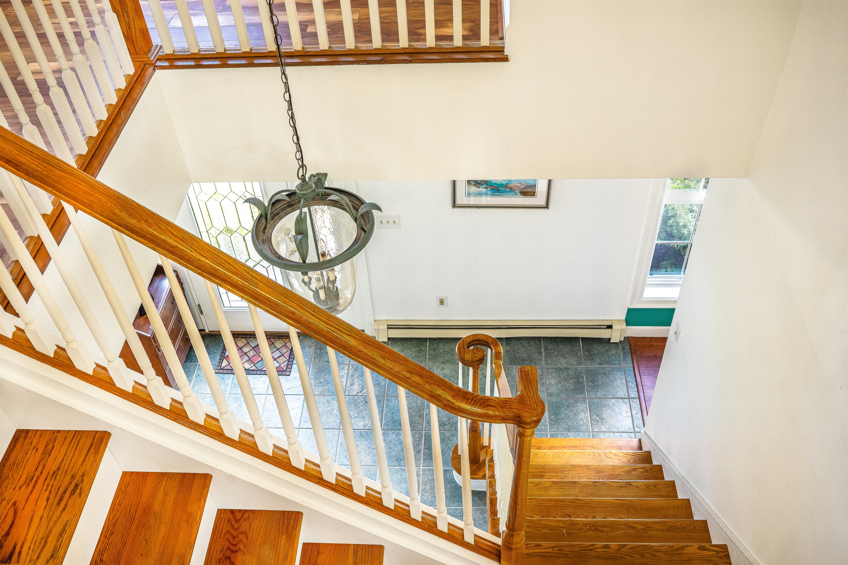Step into a grand formal foyer that sets the tone for your Southwest Harbor stay. This colonial-style entryway features a turning oak staircase and a custom lighting fixture, offering a bright, welcoming arrival for your Acadia National Park getaway.