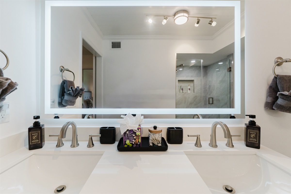Spacious primary bathroom with double vanity, LED-lit mirror, and modern walk-in glass shower