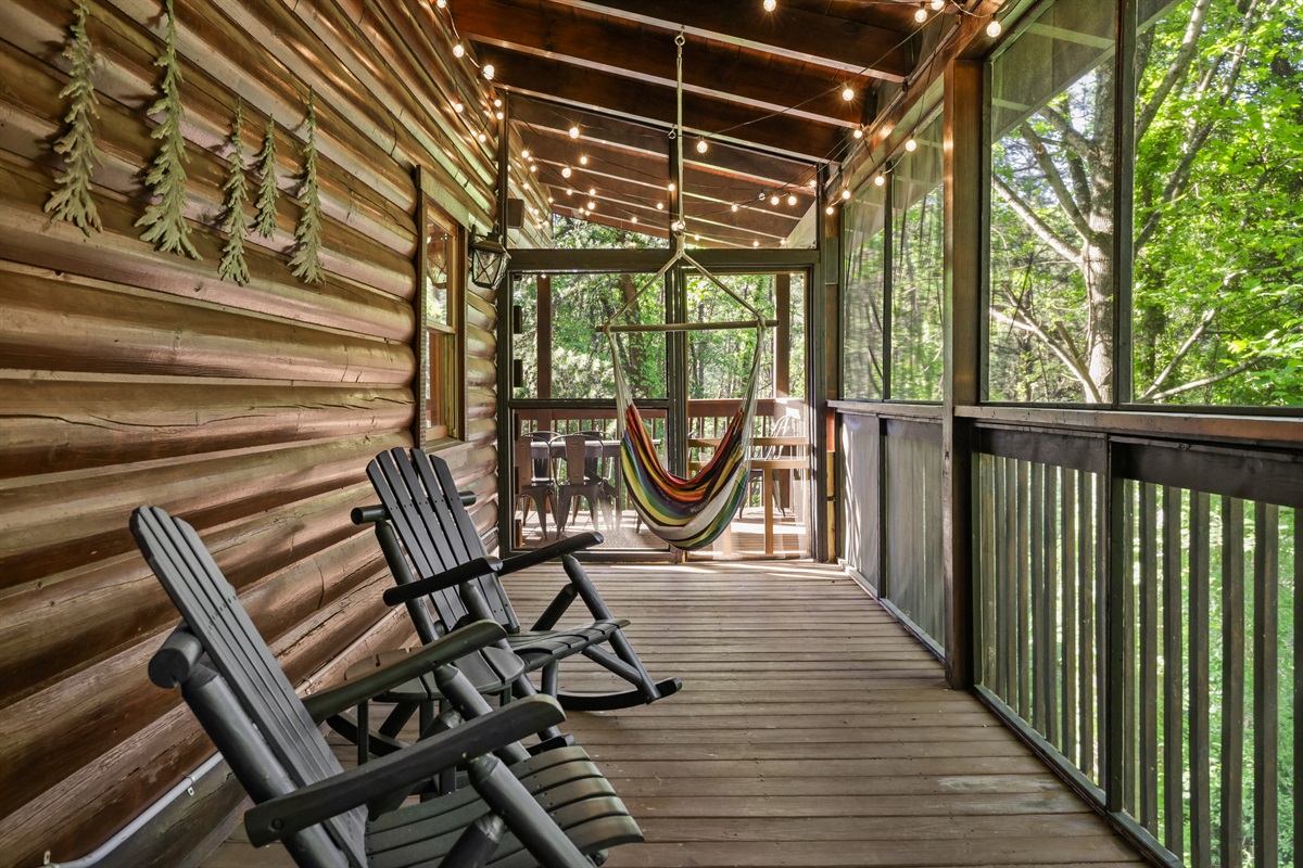 Screened in porch area with rocking chairs and a hammock