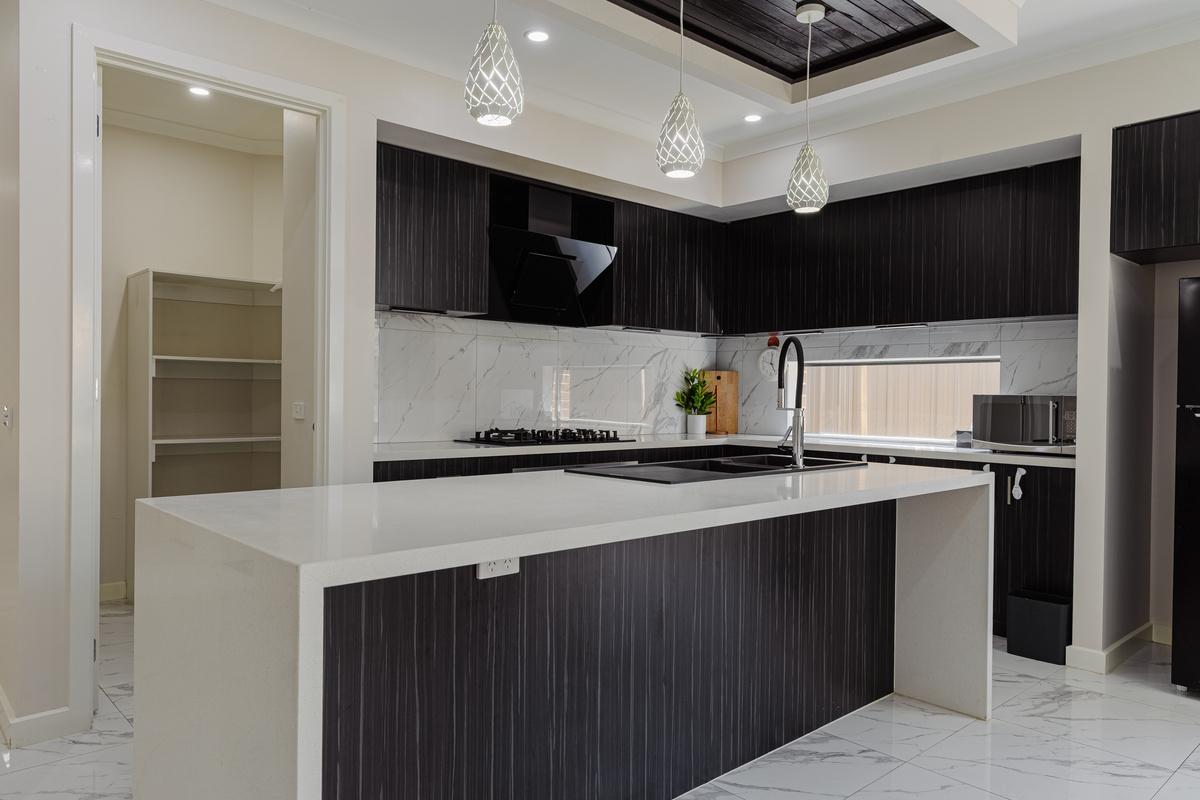 The kitchen at Willows Stays Holiday gives the home a central cooking space, with a large island bench and easy connection to the pantry.