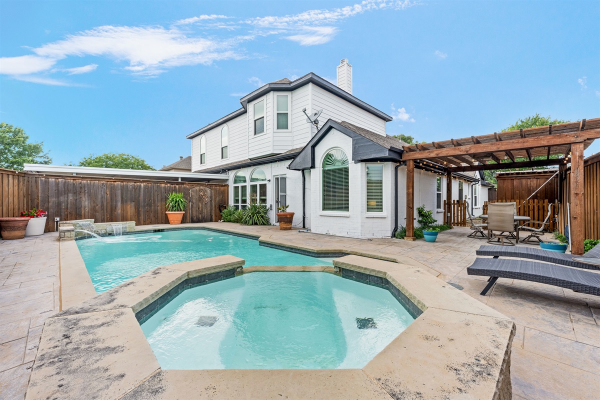 Private resort-style backyard with sparkling pool, spa fountain, and ambient string lighting.