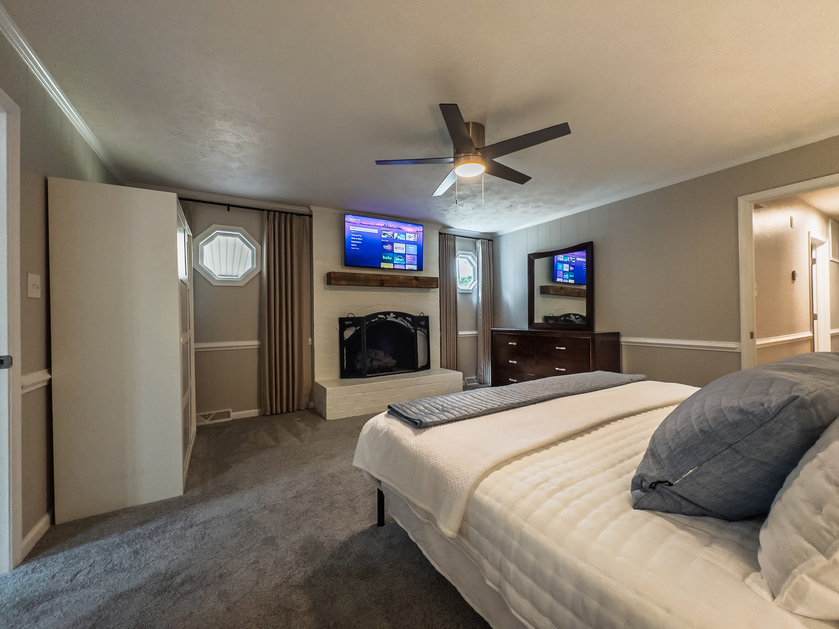 King bed, 55" Smart TV, ceiling fan, two led light nightstands with multiple charging ports, two multi light function lamps, blackout curtains, dresser, wardrobe closet, full length mirror, stylish brick fireplace - not in use.