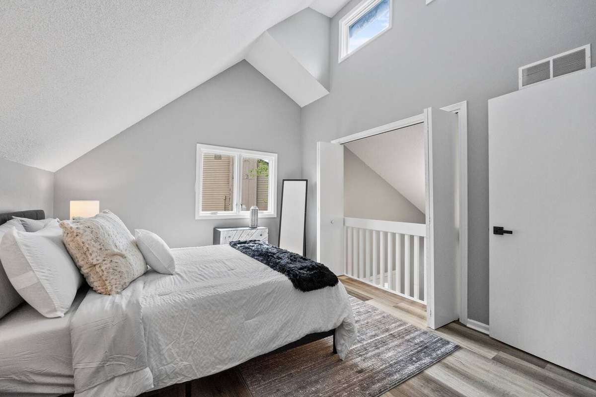 A well-lit view of the bedroom featuring a sleek mirror, adding depth and style to the space while enhancing the room's ambiance.
