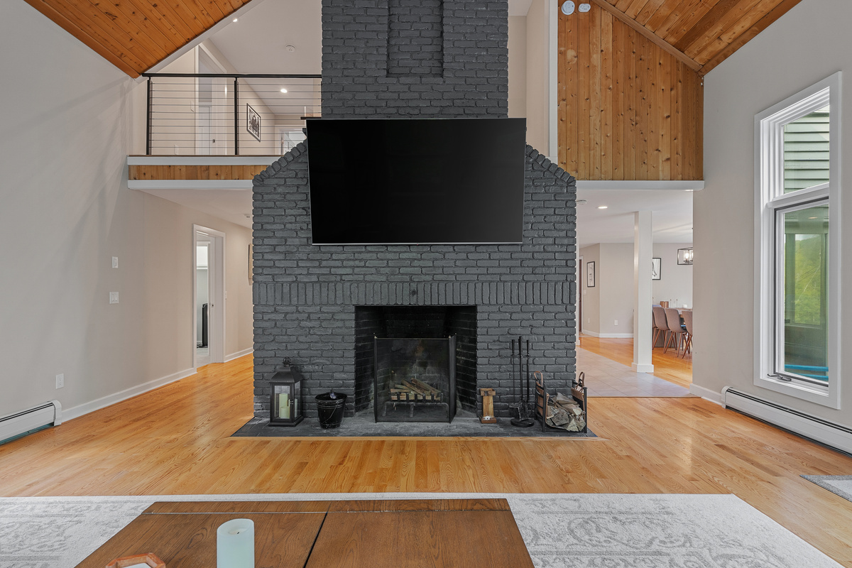 Two-story brick fireplace and loft overlook in the living room of this Winhall, Vermont ski house
