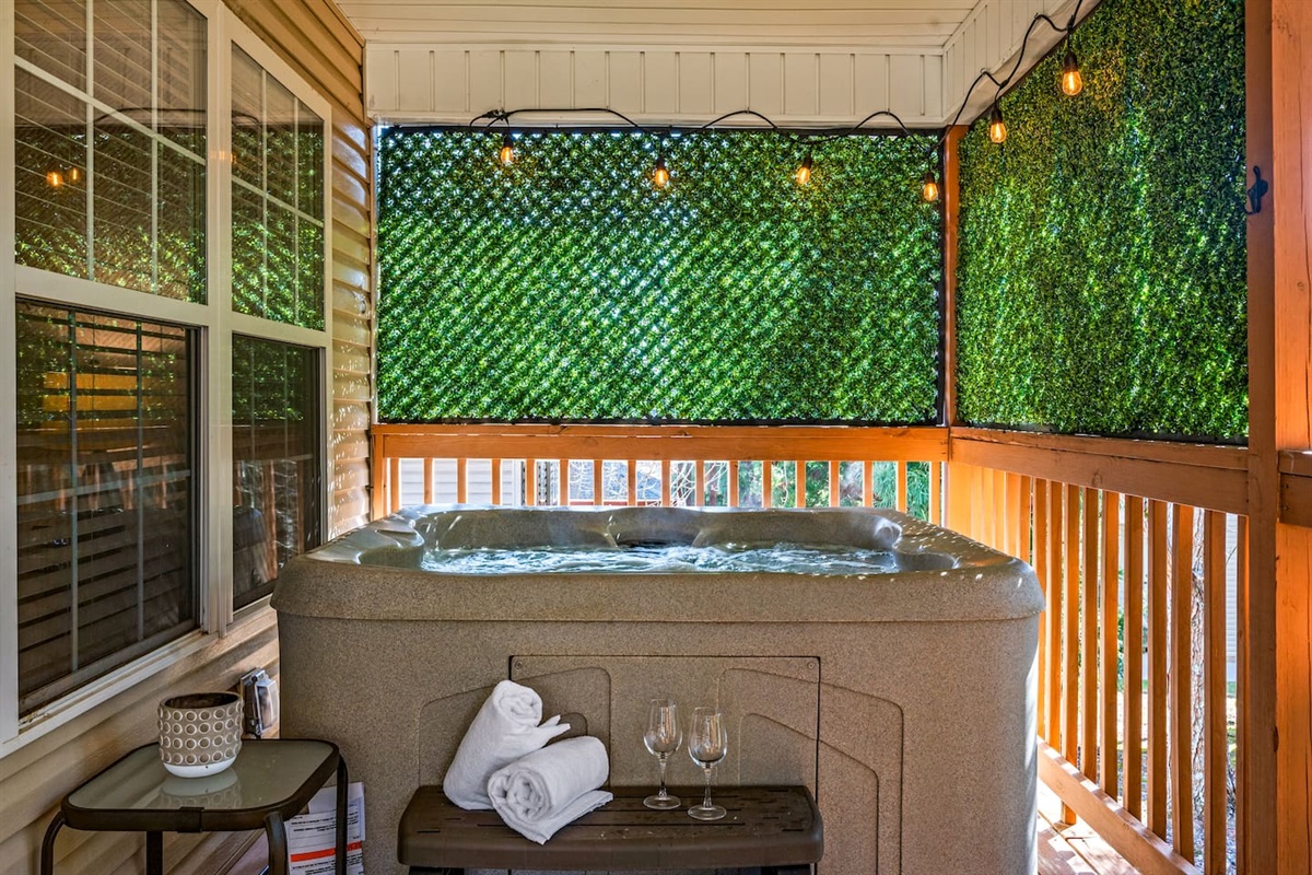 Enjoy your own private hot tub retreat, surrounded by lush greenery for added privacy. Perfect for relaxing after a long day, this cozy space features soft lighting, fresh towels, and even wine glasses for a peaceful soak under the stars.
