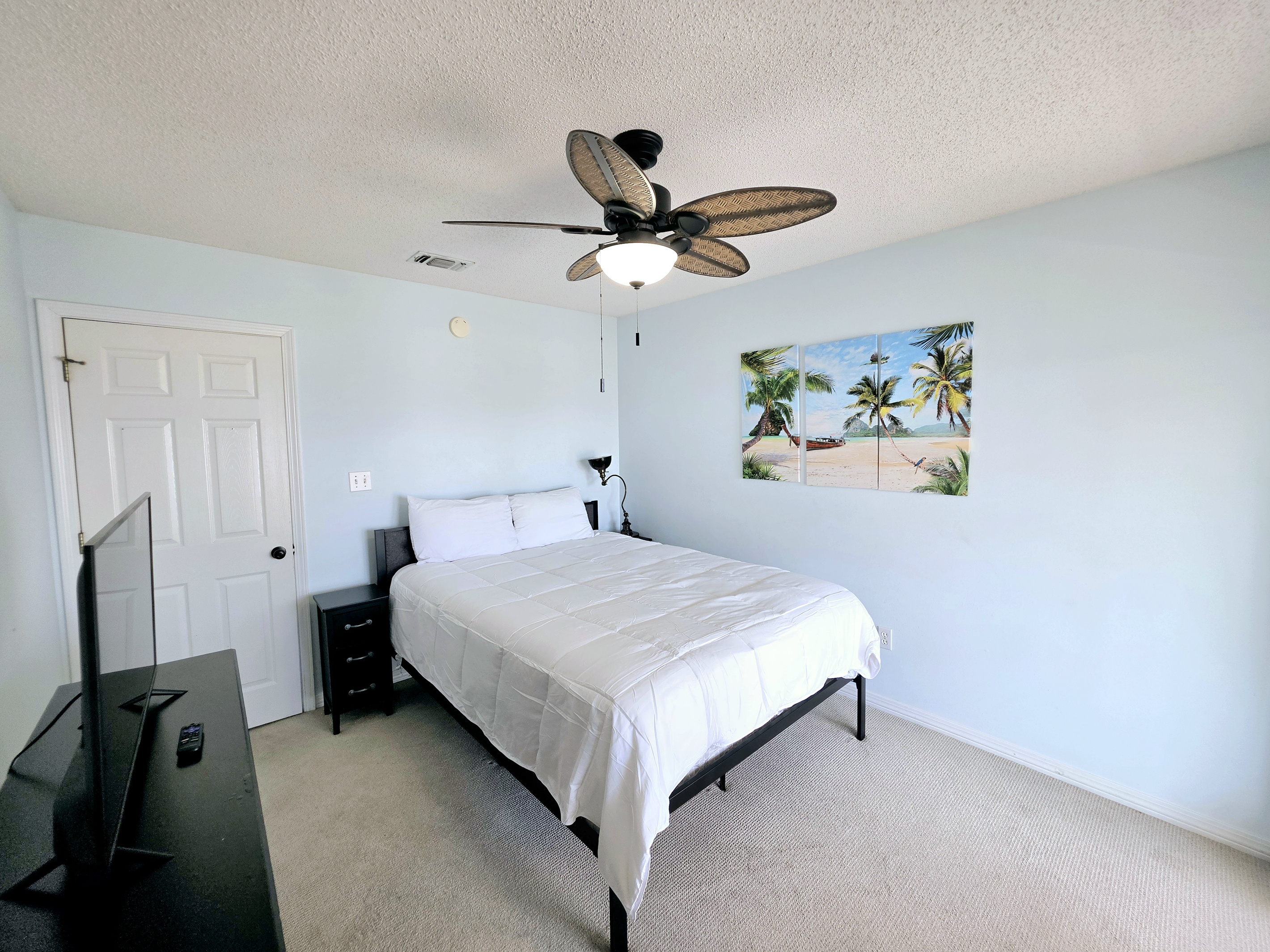 Bedroom with ceiling fan and beach-themed art