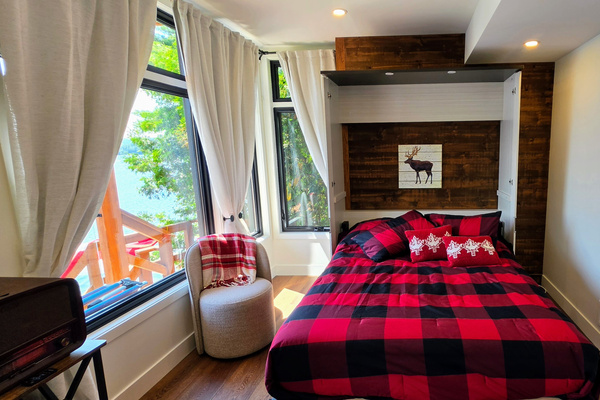 Lower level Murphy bed pulled out with view over deck and lake