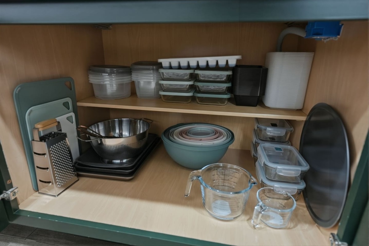Well-organized kitchen storage with mixing bowls, measuring cups, cutting boards, and food containers for easy meal prep.