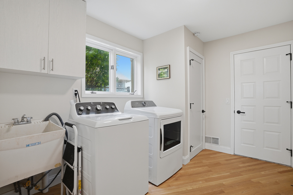 Clean, modern laundry room with washer, dryer, utility sink, and built-in storage. Bright, functional space designed for convenience during longer stays.