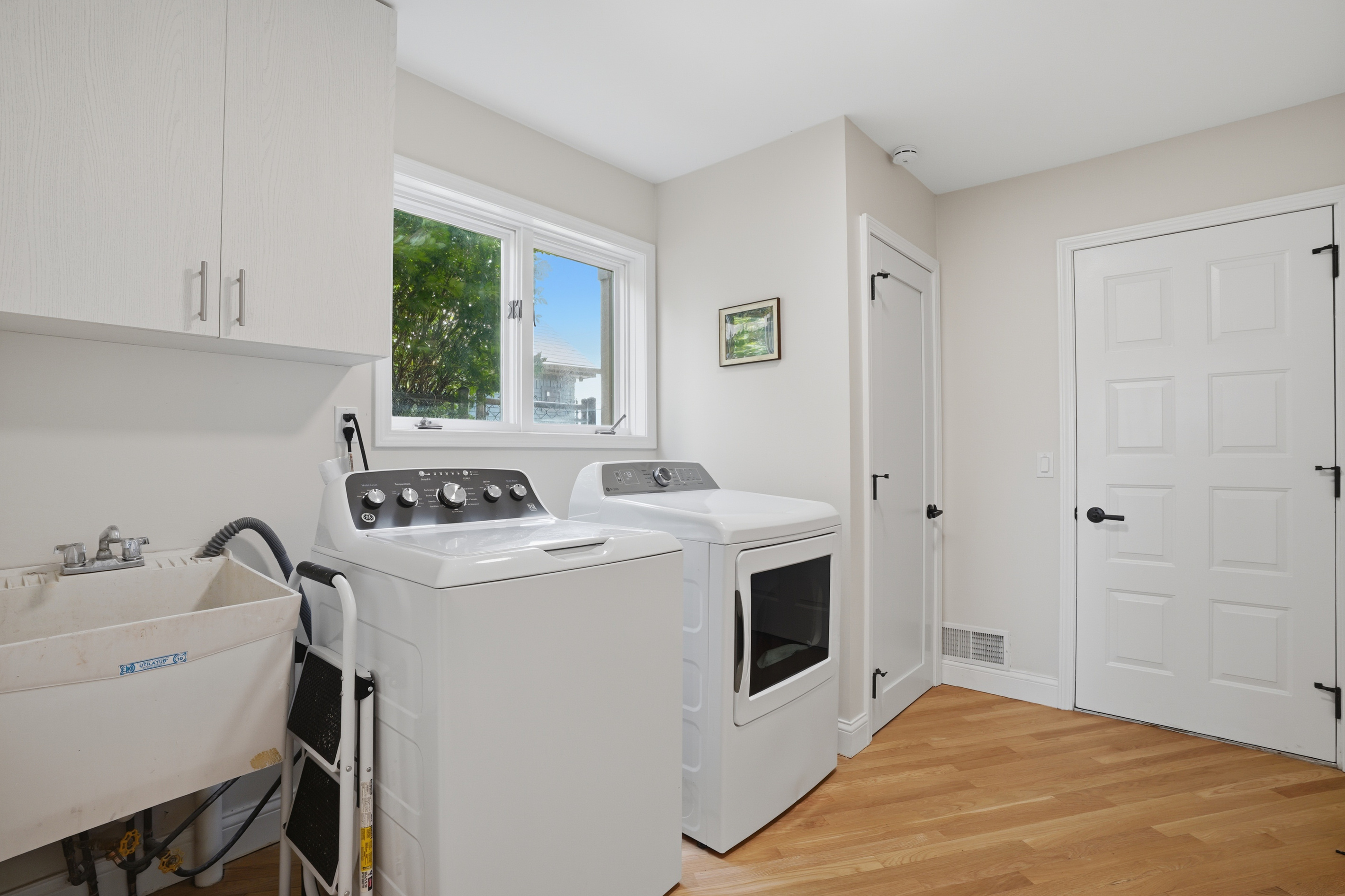 Clean, modern laundry room with washer, dryer, utility sink, and built-in storage. Bright, functional space designed for convenience during longer stays.