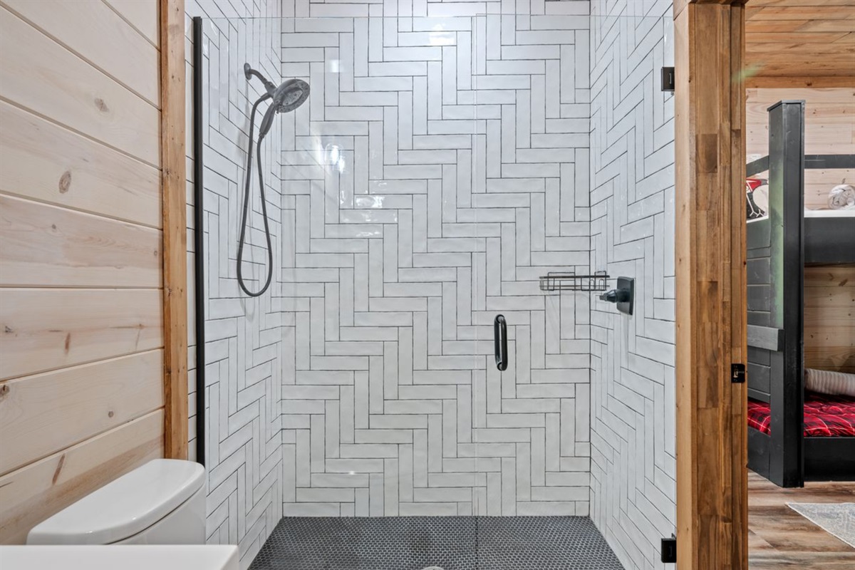 Walk-in shower with herringbone tile design in Bathroom 3.