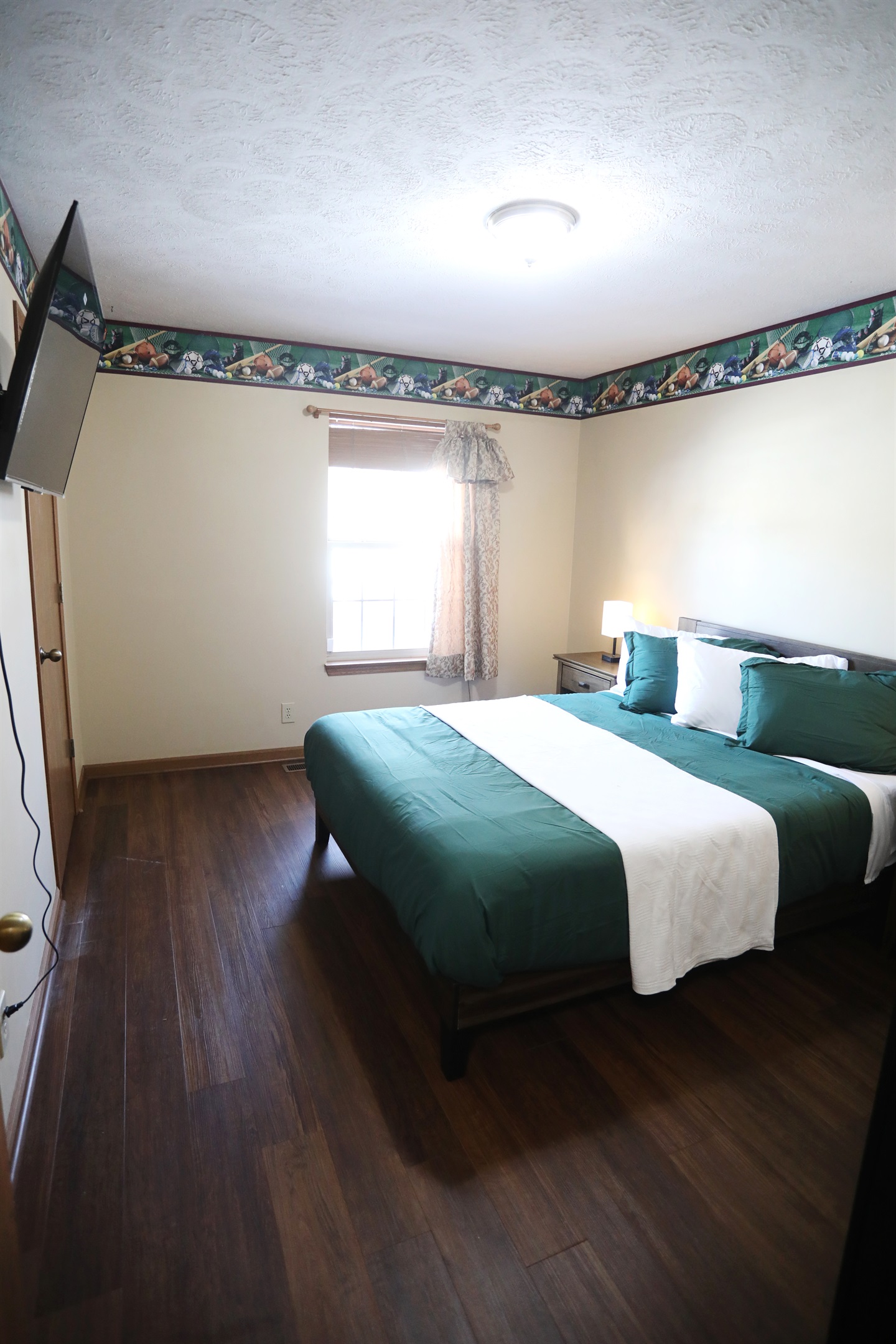 SE bedroom showing showing queen size bed, Roku TV, dresser, nightstands with touch lamps, and alarm clock